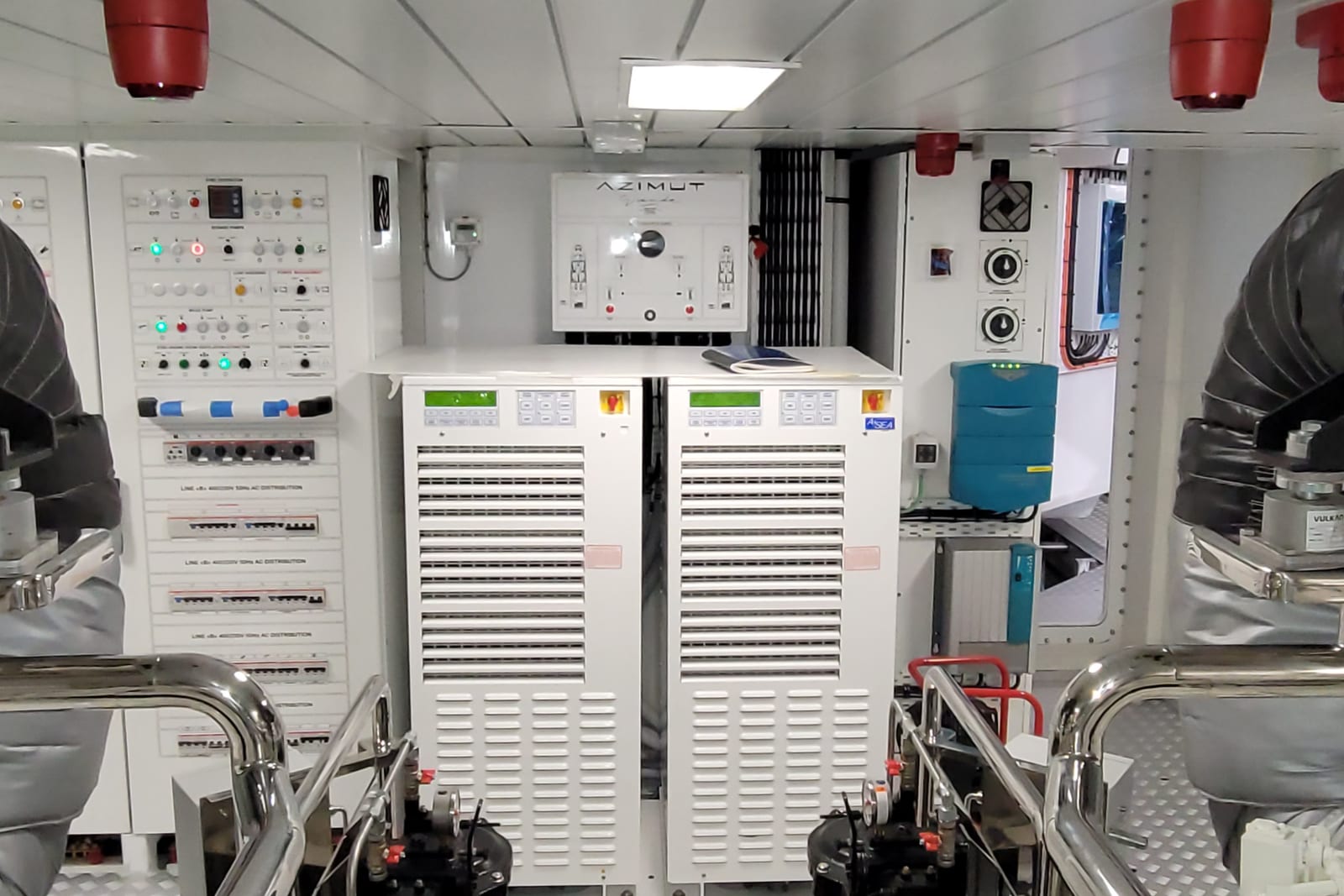 Yacht engine room with switchboards, twin insulated exhausts, and power converters.